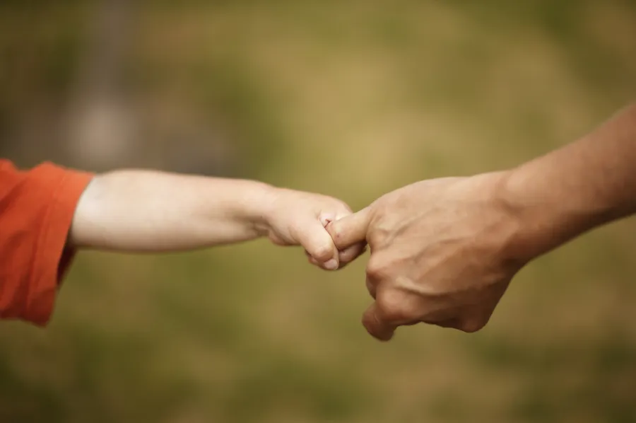Kind hält die Hand des Vaters